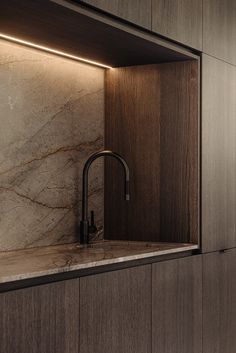 a kitchen with marble counter tops and wooden cabinets, along with a black faucet