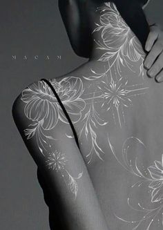 the back of a woman's body with white flowers on it