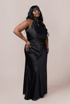 a woman in a black dress posing for the camera with her hands on her hips