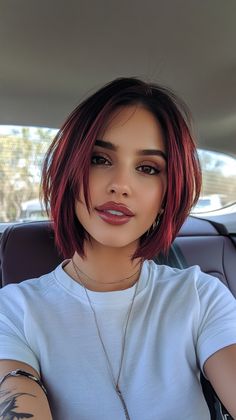 a woman with red hair sitting in the back seat of a car wearing a white t - shirt