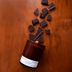 chocolate pieces are scattered around a candle on a wooden table