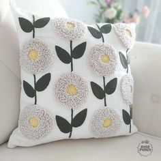 a white couch with a flowered pillow on it's back and yellow center