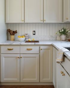 a kitchen with white cupboards and marble counter tops, along with yellow accents on the backsplash