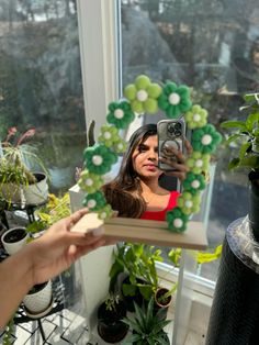 a woman taking a selfie with her cell phone in front of a green wreath