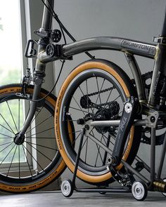 a close up of a bike parked near a window with the wheels still attached to it