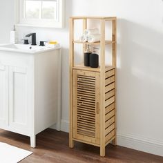 a bathroom with a sink and wooden storage unit next to a window in the corner