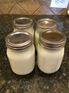 four mason jars are sitting on the counter