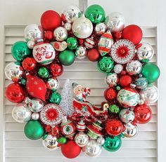 a christmas wreath with ornaments hanging on the front door, and an ornament in the middle