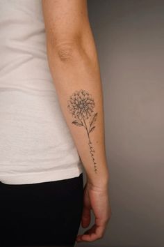 a woman's arm with a dandelion tattoo on it