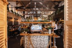 the inside of a restaurant with people sitting at tables and looking into the kitchen area