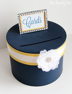 a card box with a white flower on top and a name tag attached to it