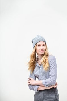 a woman standing with her arms crossed and wearing a blue hat on top of her head