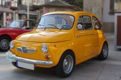 an old yellow car is parked on the street