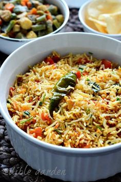 two bowls filled with rice and vegetables on top of a table next to other dishes