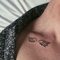 a woman's chest with an angel wing tattoo on the left side of her stomach