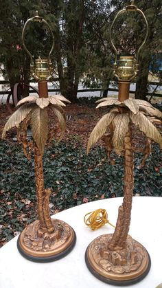 two brass palm trees are on top of a white table with gold trimmings