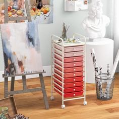 an easel with many drawers in front of paintings