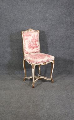 an antique chair with pink and white fabric on it's back legs, sitting against a gray background