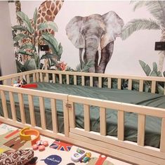 a baby's room with an elephant mural on the wall and green bedding