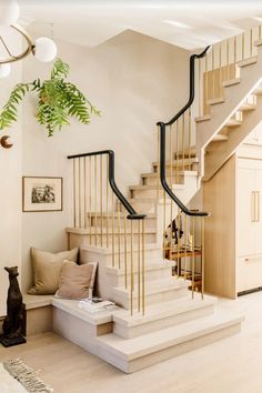 a living room filled with furniture and a stair case next to a dog sitting on the floor