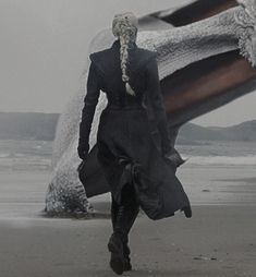 a woman walking on top of a sandy beach