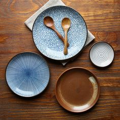 three plates and two spoons on a wooden table