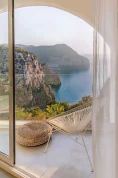 an open window with a view of the water and mountains outside it, overlooking a large body of water