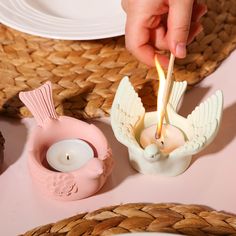 a person lighting a candle with an angel figurine