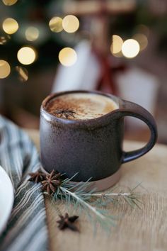 a cup of hot chocolate sitting on top of a table next to a christmas tree