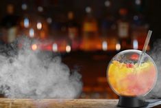 a glass bowl filled with liquid sitting on top of a wooden table next to a bar