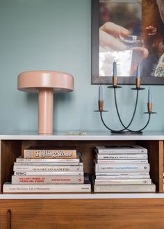 a book shelf with books and a lamp on it in front of a blue wall