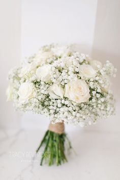 a bouquet of white roses and baby's breath is sitting on a marble surface