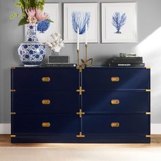 a blue and white dresser with three pictures on the wall next to it in a room