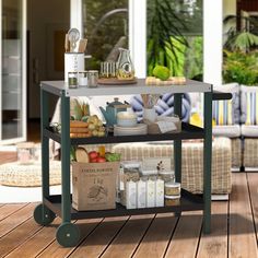 an outdoor kitchen cart with food and drinks on the outside decking area in front of a house