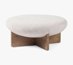 a white ottoman sitting on top of a wooden base with a cushion underneath it and a wood frame around the foot rest