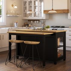 an island in the middle of a kitchen with two stools at it's base