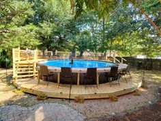 an above ground pool surrounded by wooden decking and patio furniture with chairs around it