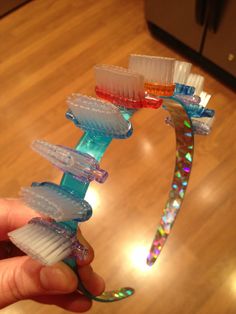 a hand holding a toothbrush holder with several tooth brushes in it on top of a wooden floor