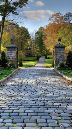 an old cobblestone road with two lamps on each side and trees in the background