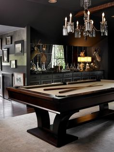 a pool table in the middle of a room with chandelier and pictures on the wall