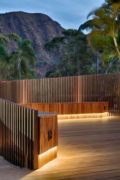 a wooden bench sitting on top of a wooden deck next to a forest covered mountain