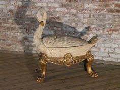 a white swan statue sitting on top of a wooden floor next to a brick wall