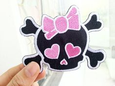 a person holding up a patch with a skull and bow on it