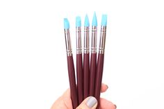 a hand holding five different colored brushes in it's left hand and the other one has blue tips