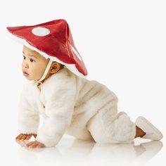 a baby wearing a red and white mushroom hat on it's head while crawling