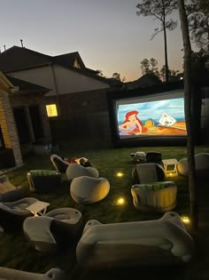 an outdoor movie is set up on the lawn in front of a house at night