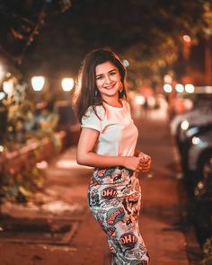 a woman is standing on the sidewalk smiling