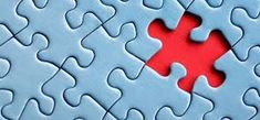 a red piece of puzzle sitting on top of a blue surface with missing pieces in the middle