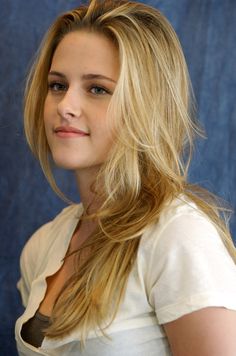 a woman with long blonde hair is posing for a photo in front of a blue background