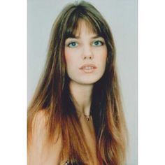 a woman with long brown hair and blue eyes posing for a photo in front of a white background